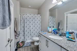 Bathroom with a textured ceiling, wood-type flooring, vanity, and toilet