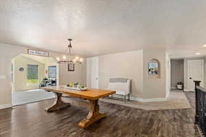 Dining room with a chandelier, dark hardwood / wood-style floors, and a textured ceiling