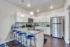 Kitchen featuring appliances with stainless steel finishes, sink, dark hardwood / wood-style flooring, and white cabinets