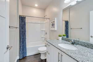 Full bathroom featuring shower / tub combo with curtain, hardwood / wood-style flooring, vanity, and toilet