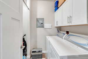 Clothes washing area with cabinets, electric panel, and independent washer and dryer