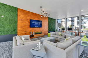 Carpeted living room with an inviting chandelier, lofted ceiling, and floor to ceiling windows