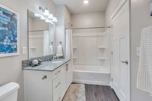 Full bathroom featuring vanity, shower / tub combo with curtain, toilet, and hardwood / wood-style flooring