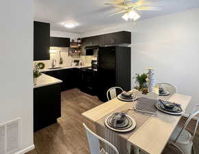 Kitchen with sink, ceiling fan, wood-type flooring, black appliances, and kitchen peninsula