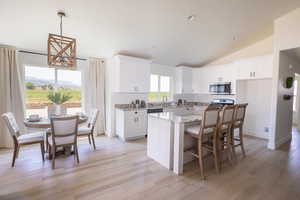 Kitchen with white cabinets, a mountain view, light wood-type flooring, lofted ceiling, and a center island