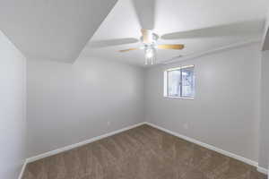 Empty room featuring ceiling fan, carpet, baseboards, and a textured ceiling