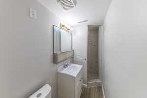 Full bath featuring visible vents, a stall shower, vanity, and wood finished floors