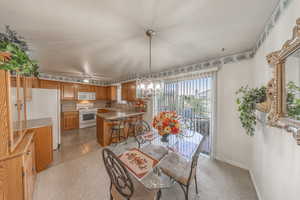 Tiled dining room with ceiling fan with notable chandelier and sink