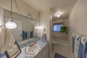 Bathroom with tile patterned flooring, a tub to relax in, vanity, and toilet