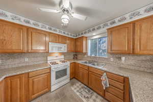 Kitchen featuring ceiling fan, tasteful backsplash, white appliances, sink, and light tile patterned floors