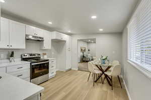 Kitchen with light wood-type flooring, electric range, and white cabinetry