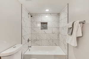 Bathroom featuring tiled shower / bath and toilet