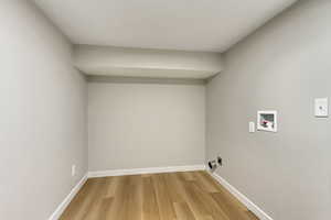 Laundry area with light wood-type flooring and hookup for a washing machine