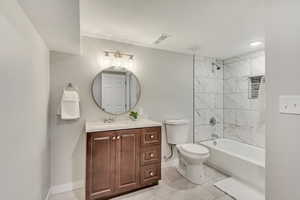 Full bathroom featuring toilet, vanity, and tiled shower / bath combo