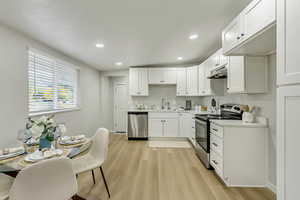 Kitchen featuring light hardwood / wood-style floors, white cabinets, appliances with stainless steel finishes, and sink