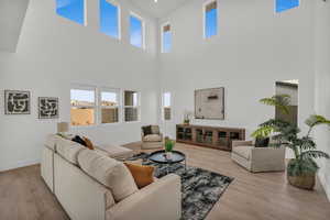 Living room with a towering ceiling and light hardwood / wood-style floors