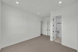 Unfurnished bedroom featuring ensuite bathroom and light colored carpet