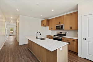 Kitchen with dark hardwood / wood-style flooring, a kitchen island with sink, sink, and stainless steel appliances