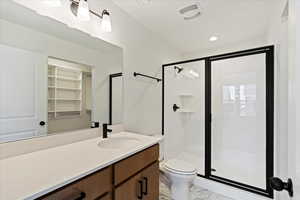 Bathroom featuring vanity, toilet, and an enclosed shower