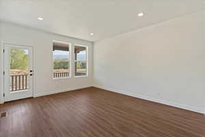 Spare room featuring a textured ceiling and dark hardwood / wood-style floors