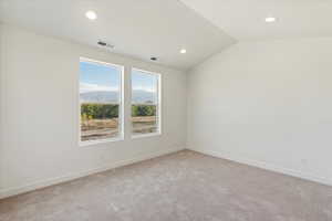 Spare room featuring lofted ceiling and light carpet