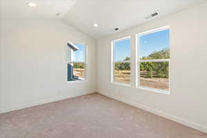 Unfurnished room featuring light carpet and vaulted ceiling