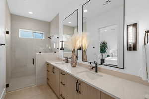 Bathroom featuring a shower with door, vanity, and tile patterned floors