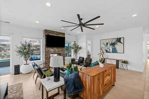 Living room with a wealth of natural light, a fireplace, ceiling fan, and light tile patterned flooring