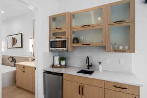 Kitchen with light brown cabinetry, sink, and decorative backsplash