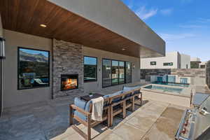 View of patio featuring pool water feature and an outdoor stone fireplace