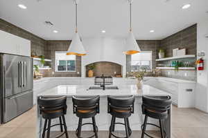 Kitchen with light tile patterned flooring, high end refrigerator, sink, and white cabinets