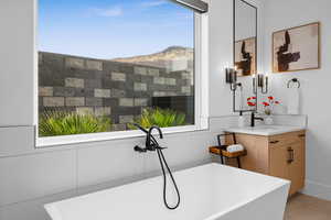 Bathroom with a tub, plenty of natural light, vanity, and a mountain view