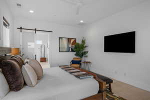 Bedroom with multiple windows, a barn door, and ceiling fan