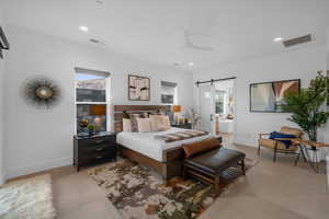 Bedroom featuring ensuite bath, a barn door, and ceiling fan