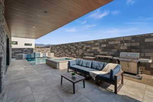 View of patio / terrace featuring a swimming pool with hot tub, an outdoor living space, a mountain view, grilling area, and pool water feature