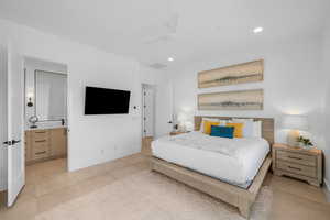 Bedroom with ceiling fan, light tile patterned floors, and ensuite bath