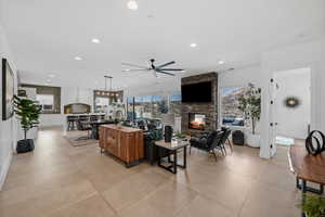 Tiled living room featuring a stone fireplace and ceiling fan