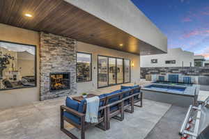 Patio terrace at dusk with an outdoor living space with a fireplace and a jacuzzi