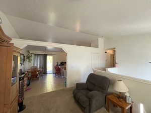 Sitting room featuring a textured ceiling, lofted ceiling, and light tile patterned floors