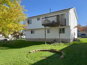 Rear view of property featuring central air condition unit and a lawn