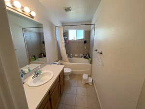 Full bathroom with shower / bath combination with curtain, vanity, a textured ceiling, tile patterned floors, and toilet