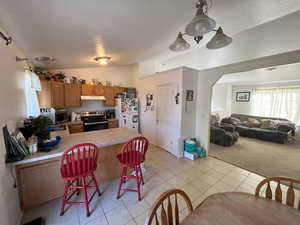 Kitchen featuring a kitchen bar, a textured ceiling, stainless steel appliances, and vaulted ceiling