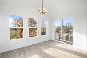 Unfurnished dining area featuring light wood-type flooring, lofted ceiling, and a chandelier