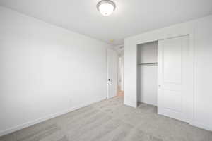 Unfurnished bedroom with light carpet and a closet