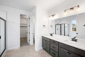 Bathroom featuring tile patterned flooring, vanity, toilet, and walk in shower