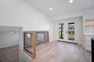 Unfurnished living room featuring french doors, light hardwood / wood-style floors, and vaulted ceiling