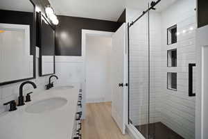 Bathroom featuring walk in shower, hardwood / wood-style flooring, dual sinks and vanity