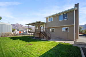 Rear view of house featuring a mountain view, a yard, and a patio