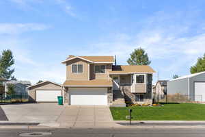 Split level home featuring a garage and a front lawn