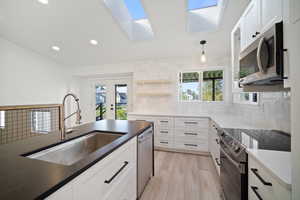 Kitchen featuring stainless steel appliances, sink, tasteful backsplash, and white cabinetry